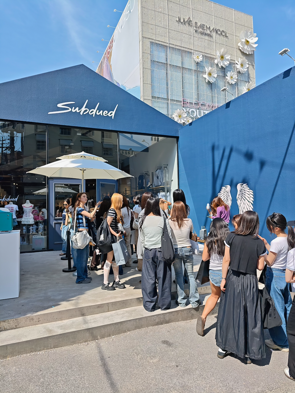 Subdued 户外快闪店前排着长队，有人蹲下休息